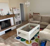 Living room in a cabin with a comfortable sofa, fireplace, and wooden decor flooring.