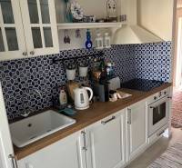 White kitchen with blue tiles, wooden decor, and rustic details in a cottage.