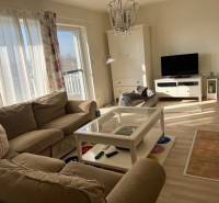 Living area in a cabin with comfortable seating, a television, and a wooden decor floor.