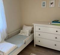 A children's room in a cottage with a crib, a dresser, and a floor with a wooden decor.