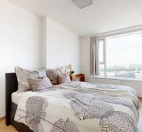A bright bedroom with a bed, mirror, and wooden decor flooring in a 3-room apartment.