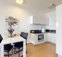 A kitchen in a 3-room apartment with white cabinets, a dining table, and a wooden decor floor.