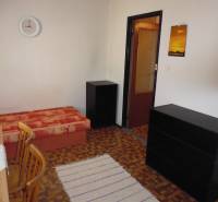 A room in a one-room apartment with carpet decor and furniture.