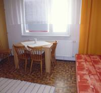 Dining area with wooden chairs and a table in a studio apartment with wooden decor.