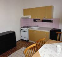 A kitchen in a studio apartment with a wooden decor floor and a dining table.