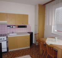 A kitchen in a studio apartment with a simple wooden decor and a dining table.