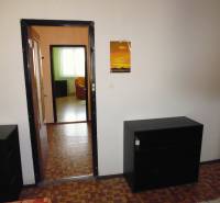 Room in a one-room apartment with a wooden decor floor, tiled stove, and furniture.