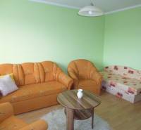 Green walls, an orange sofa, and a wooden decor floor in a studio apartment.