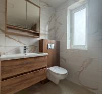A bathroom in a family house with a mirror, a sink, and ceramic tiles.