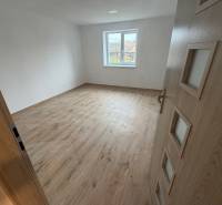A room in a family house with a wooden decor floor and white walls.