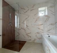 Bathroom in a family house with marble-patterned tiles and a shower enclosure.