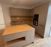 A kitchen in a family house with a wooden decor floor and kitchen cabinets.