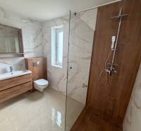 A bathroom with tiles and a wooden decor floor, with a shower and a toilet.