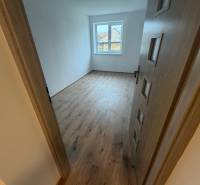 A room in a family house with a wooden decor floor and a large window.