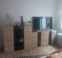 Living room in a family house with furniture, a television, and a wooden decor floor.