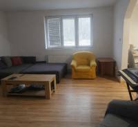 Living room in a family house with a wooden decor floor, a sofa, and a piano.