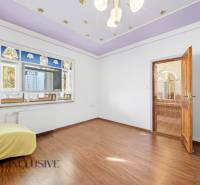 A room with a wooden decor floor, stained glass windows, open doors to the bathroom.