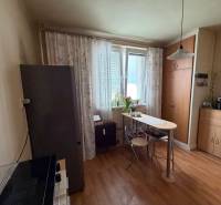 A kitchen in a 3-room apartment with a wooden decor floor, a table, and cabinets.