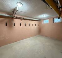 A small room in a 3-room apartment with hangers on the wall and pipes on the ceiling.
