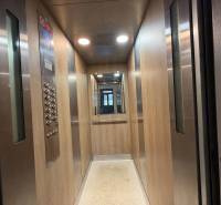Interior of an elevator with wood decor and a mirror, in a multifunctional building.