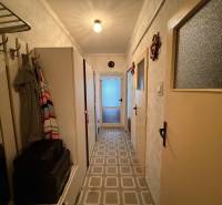 A narrow hallway in a 3-room apartment with a coat rack, a wardrobe, and a patterned floor.