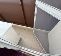 Balcony in a 3-room apartment with tiles and a carpet by the door.