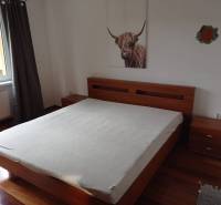 A bedroom with a wide bed and a wooden decor floor in a 2-room apartment.
