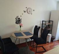 Dining room in a 2-room apartment with a table, chairs, and a wooden decor floor.