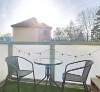 A balcony with two chairs and a table, with green grass on the floor.