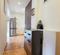 A hallway with a chest of drawers, a wooden decor floor, opens up the space in a 2-room apartment.