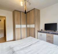 Bedroom in a two-room apartment with a wooden decor floor, built-in wardrobe, and dresser.