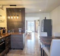 A kitchen in a 2-room apartment with a wooden decor floor, a dining table, and appliances.