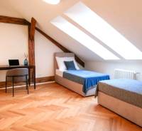 Attic room in a 3-room apartment with skylights, a work desk, and beds.