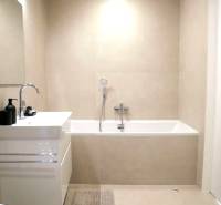 A bathroom with a bathtub and a sink in a 3-room apartment with simple furnishings.