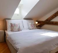 Attic bedroom in a 3-room apartment with exposed wooden beams and subdued lighting.