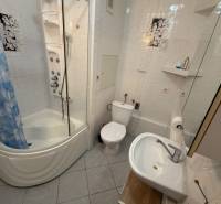 Bathroom in a 2-room apartment with a corner bathtub, toilet, and sink.