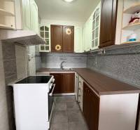 A kitchen in a 2-room apartment with a combination of wooden cabinets and gray tiles.