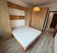 Bedroom in a two-room apartment with a double bed, built-in wardrobes, and a floor with a wooden decor.