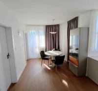 Dining area in a 2-room apartment with a round table and wooden decor flooring.