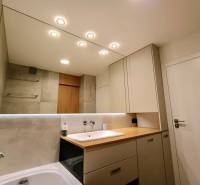 Bathroom in a 2-room apartment with a large mirror, sink, and bathtub.