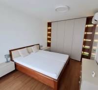 Bedroom in a two-room apartment with a wood-patterned floor and a built-in wardrobe.