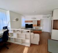A bright living space with wood-patterned flooring, white furniture, and a desk.