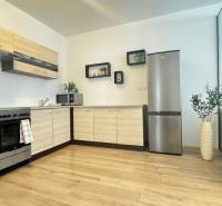 A kitchen in a 3-room apartment with a wooden decor floor and wall shelves.
