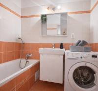 Bathroom with a bathtub, sink, and washing machine in a 3-room apartment.
