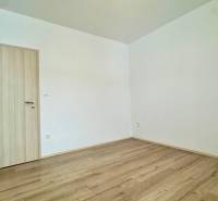 A room in a 3-room apartment with a wooden decor floor and white walls.