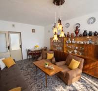 A living room with wooden furniture, a sofa, armchairs, and porcelain decorations in a three-room apartment.