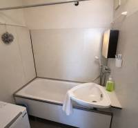 A bathroom in a 3-room apartment with a bathtub, sink, and washing machine.