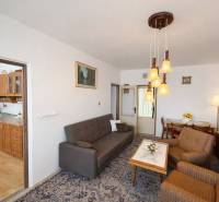 Living room with rustic furniture and wood-patterned flooring in a three-room apartment.