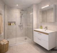 Bathroom with a shower, sink, and laundry basket in a 3-room apartment.
