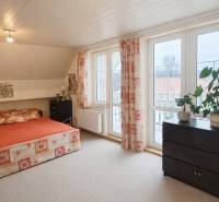 Bedroom in a family house with a bed, cabinet, large windows, and plants on the windowsill.